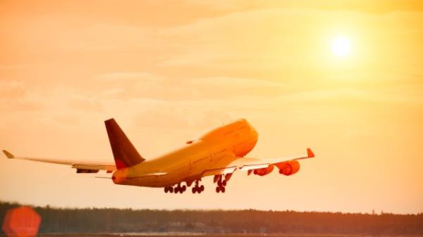 A commercial jetliner taking off at sunset on a hot day